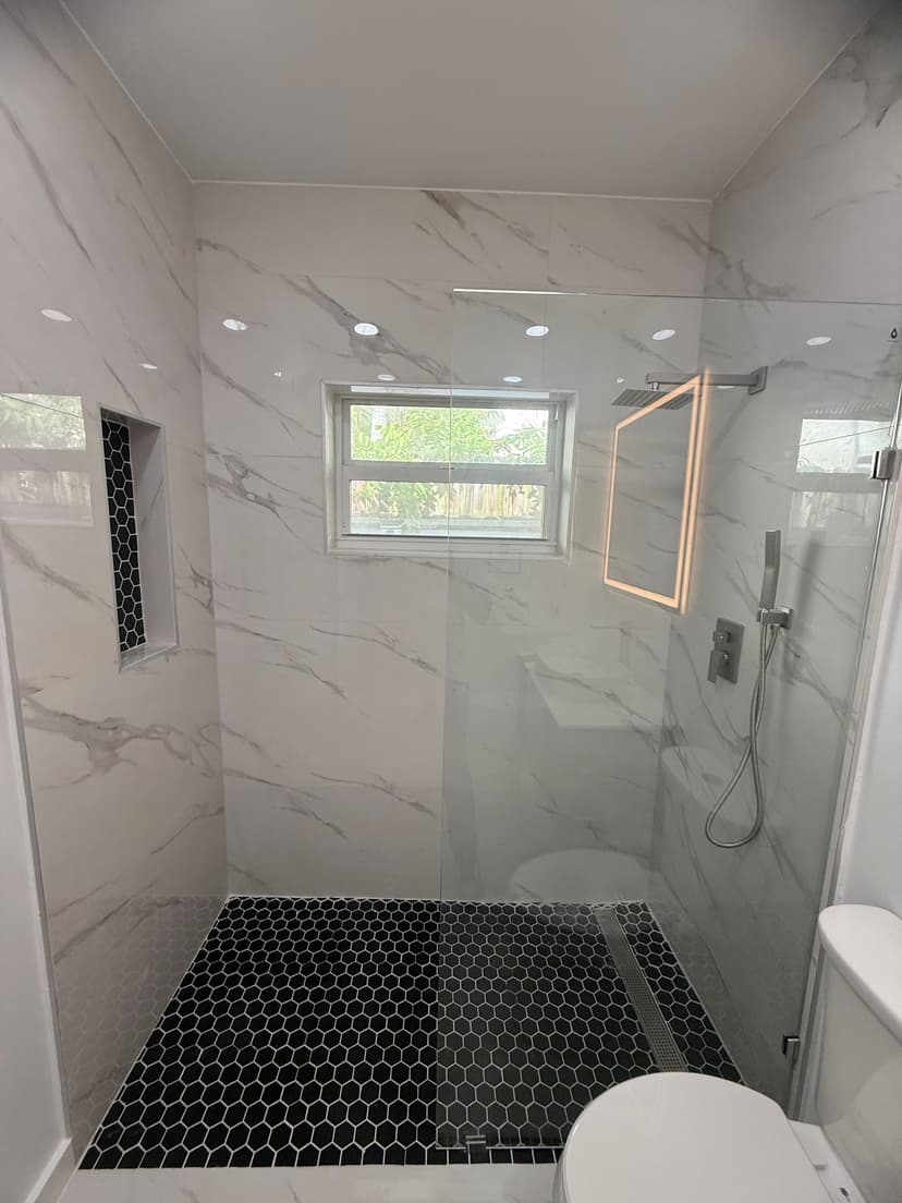 Overview of the finished walk-in shower with black hex tiles and linear drain.