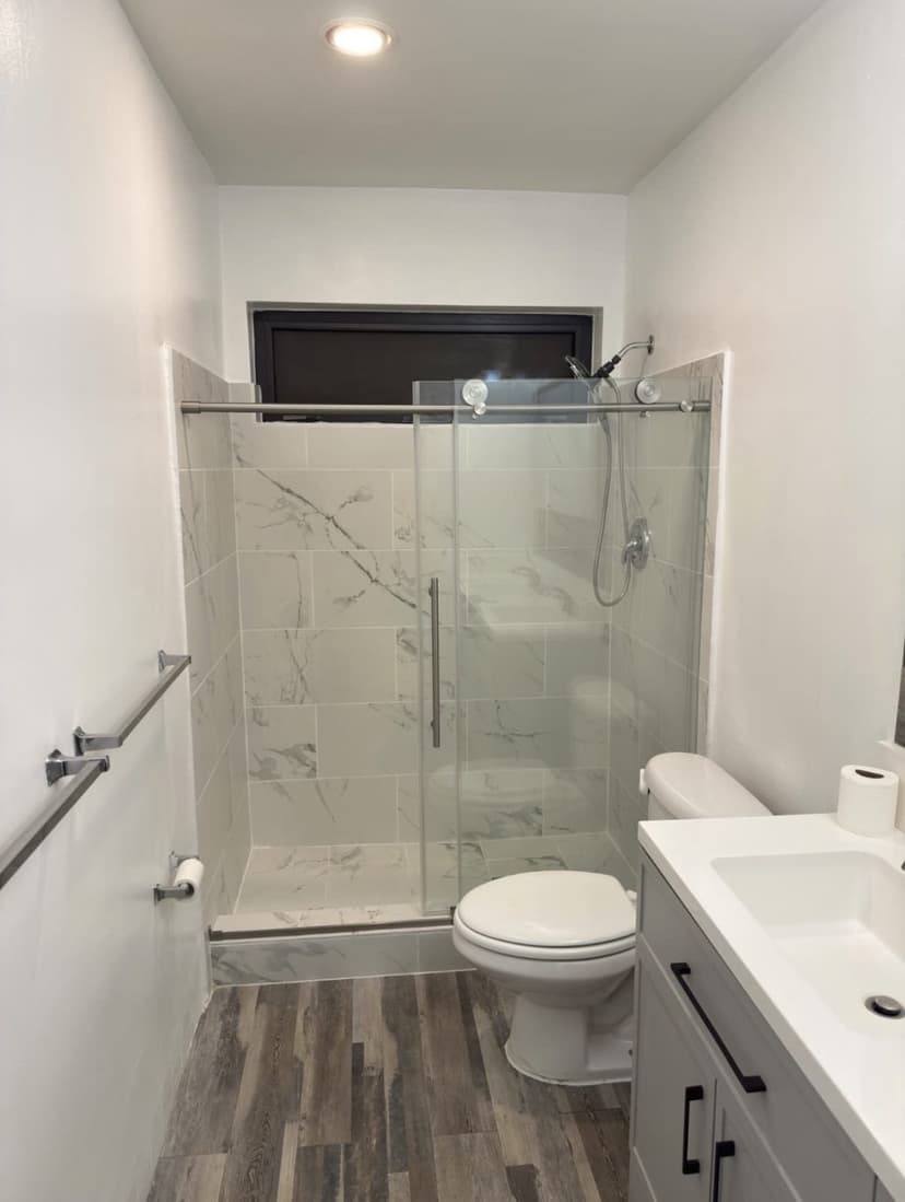 Marble-look tile shower with sliding glass doors and a new vanity.